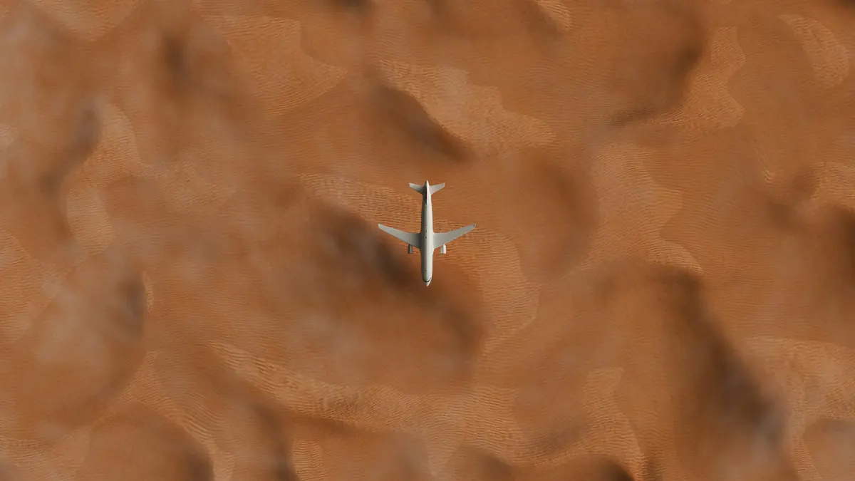 A business jet crossing rippled desert dunes, seen from above